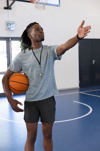 Basketball coach directing team on indoor court