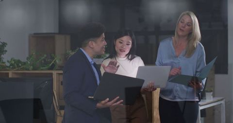 Diverse office team collaborating on laptops and documents