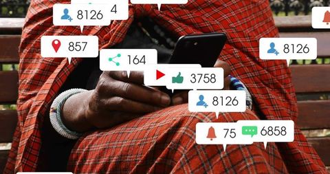 Senior man tapping smartphone in red checked wrap and beaded bracelets with social notifications