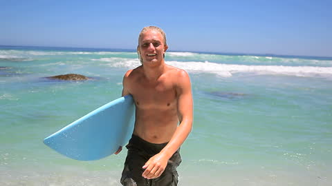Blonde Surfer Man with Blue Surfboard on Sunny Beach
