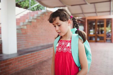 Young Schoolgirl Feeling Upset in School Corridor