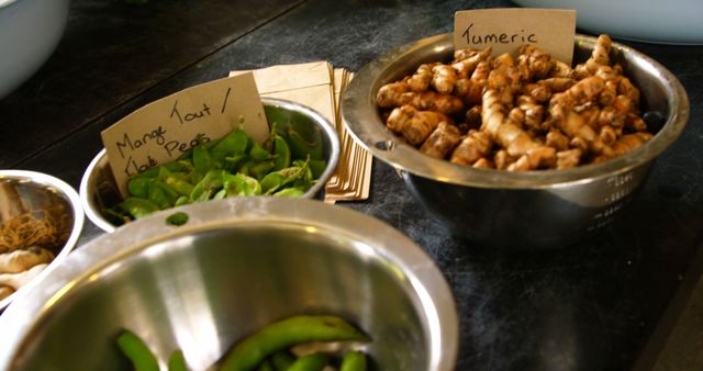 Photo depicting fresh green beans and turmeric at a market stall. Includes handwritten labels identifying the produce. Useful for illustrating topics on fresh produce markets, healthy eating, cooking ingredients, and raw foods.