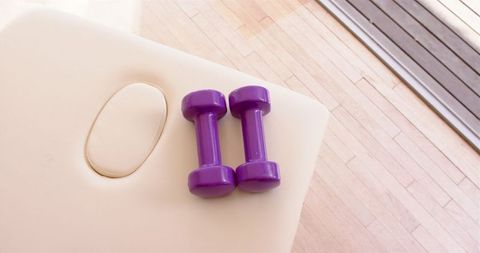 Purple dumbbells on massage table in physio clinic for wellness and rehab