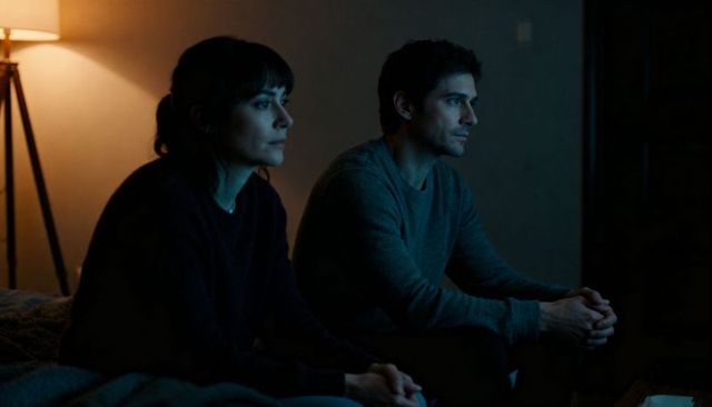 Couple sitting on couch watching tv at night warm lamp light intimate quiet evening moment