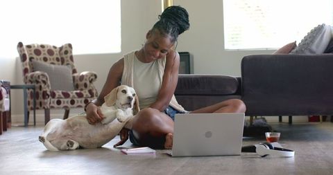 Woman Relaxing with Dog While Using Laptop at Home