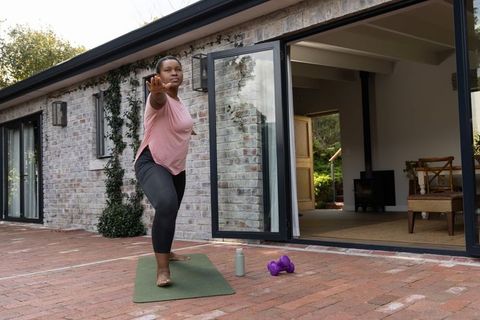 African american woman practicing yoga on patio, stretching for balance and strength