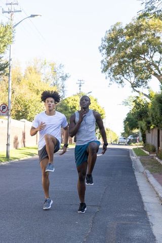 Diverse male friends performing high-knee running drills outdoors