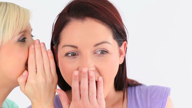 Two young women sharing a secret in a playful and conspiratorial manner. Their expressions suggest trust and intimacy in their relationship, highlighting aspects of friendship and communication. Useful for articles or campaigns about social relationships, teamwork, or confidential exchanges.