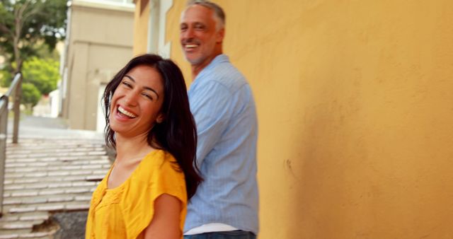 Happy couple smiling outdoors near yellow wall - Download Free Stock Images Pikwizard.com