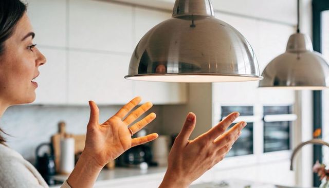 Woman gesturing and pointing at pendant lamps over modern minimalist kitchen island