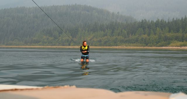 Excited Woman Wakeboarding on Beautiful Lake Surrounded by Forest - Download Free Stock Images Pikwizard.com