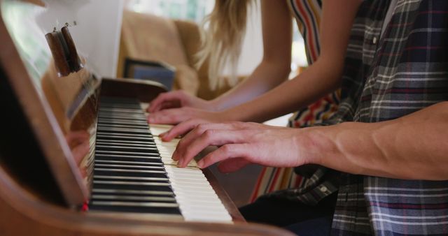 Couple sitting closely sharing a piano seat, playing piano together. Focus on their hands and the piano keys. Perfect for illustrating teamwork, music lessons, or romantic activities. Useful for lifestyle blogs, music education, relationship tips or advertising musical instruments.