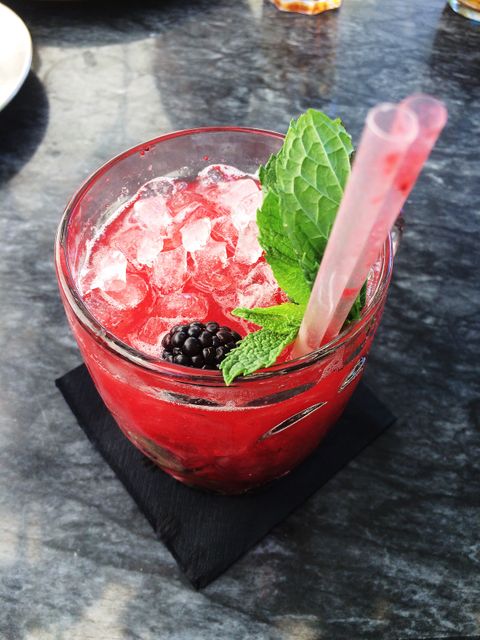 Colorful berry cocktail with crushed ice and fresh mint leaves, great for beverage advertisements, summer drink menus, cocktail recipes, and lifestyle blogs. This close-up view emphasizes the refreshing and appetizing nature, ideal for use in visuals promoting outdoor and summer events.