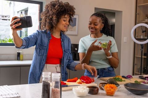 African American Friends Filming and Preparing Healthy Recipe in Modern Kitchen