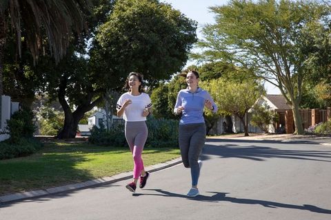 Two female friends jogging in suburban neighborhood