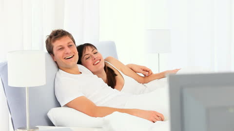 Happy Couple Enjoying Movie Together in Cozy Bedroom
