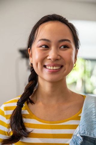 Stylish young asian woman smiling indoors with casual fashion