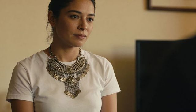Woman wearing oversized tribal coin necklace with white t-shirt in warm interior portrait