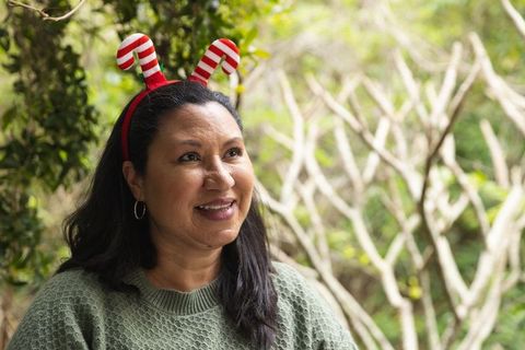 Smiling woman wearing candy cane headband in garden setting
