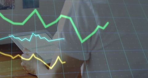 Business Professional Analyzing Data on Desktop with Line Graph Overlay