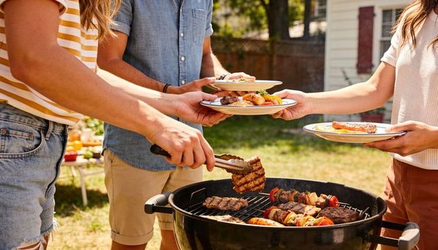 Backyard summer barbecue friends grilling burgers and skewers at charcoal cookout gathering