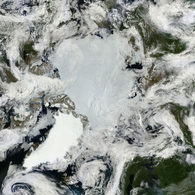 This mosaic image shows the Arctic ice and summer lands near the North Pole, captured by NASA’s Terra satellite on June 30, 2011. The blue-white polar ice cap and the bright white ice on Greenland are prominent, with billowing clouds swirling over the region. This high-definition image is useful for understanding climate patterns, studying ice melt, and observing cloud formations.
