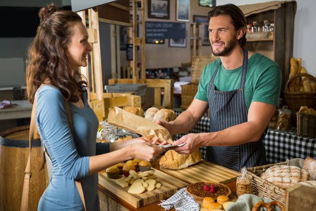 Customer paying for bread at bakery counter. Ideal for illustrating small business transactions, customer service, and local market shopping experiences. Useful for marketing materials, websites, and advertisements related to bakeries, retail, and customer service training.