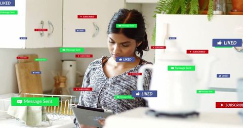 Woman engaging with social media messaging on tablet in kitchen