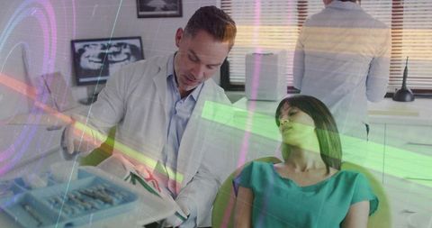 Dentist examining reclining patient with dental x-ray monitor and instruments