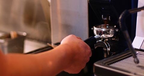 Close-up of barista preparing espresso with coffee maker