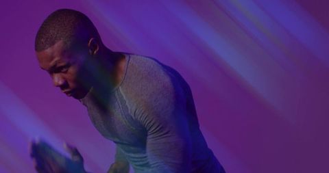 Futuristic athlete powering forward under neon purple and teal light streaks