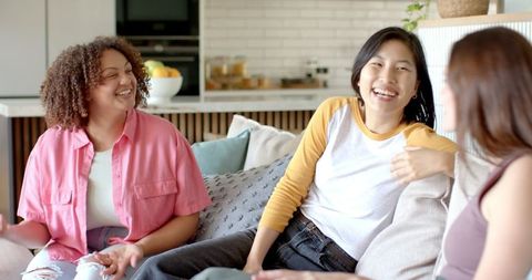 Diverse Female Friends Laughing on Cozy Sofa at Home