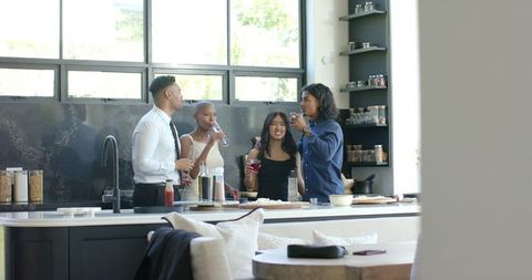 African American Friends Gathering in Modern Kitchen Drinking, Mingling and Laughing