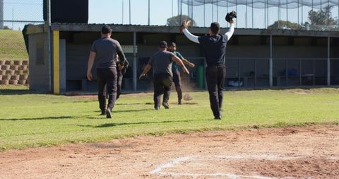 Baseball teammates walking across infield toward dugout kicking up dust