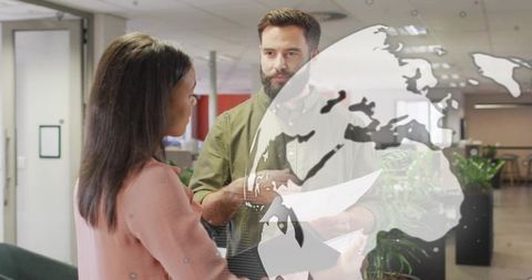 Team discussing documents in modern office with globe overlay for global collaboration