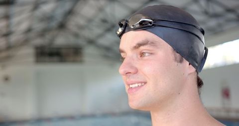 Smiling male swimmer ready by indoor pool