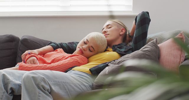 Happy diverse female couple embracing and lying together in living room. spending quality time at home.