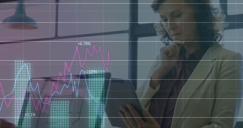 Mature businesswoman analyzing digital graphs on tablet in modern office