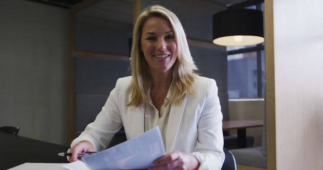 Businesswoman Smiling and Reviewing Documents in Modern Office - Download Free Stock Images Pikwizard.com