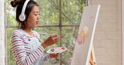 Painting pastel portrait while listening to music in sunlit studio wearing denim overalls