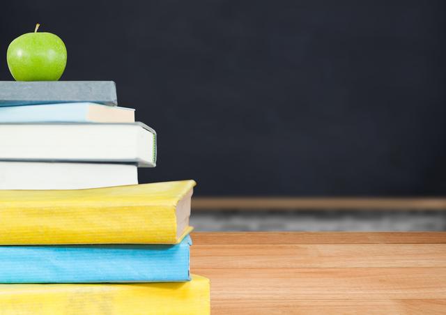 This image depicts an apple placed on top of a stack of books with a blackboard in the background. It is ideal for use in educational materials, school websites, back-to-school promotions, and academic presentations. The image conveys themes of learning, knowledge, and education, making it suitable for teachers, students, and educational institutions.