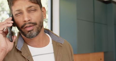 Mature Indian Man on Smartphone by Window