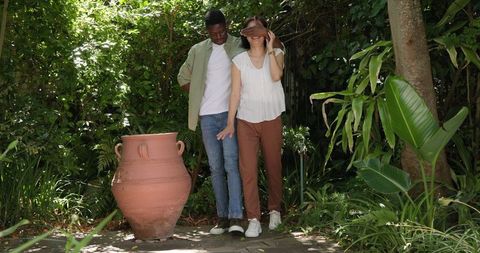 Romantic gesture: man surprising woman with flowers in lush garden