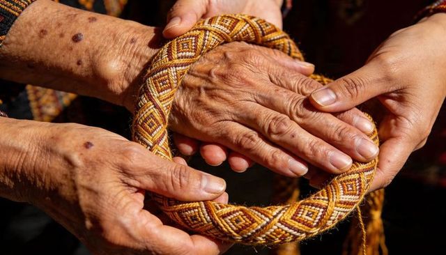 Elderly hands holding handwoven braided ring with geometric diamond textile pattern