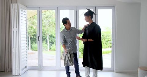 Graduate in Cap and Gown Honored by Proud Parent at Home Celebration