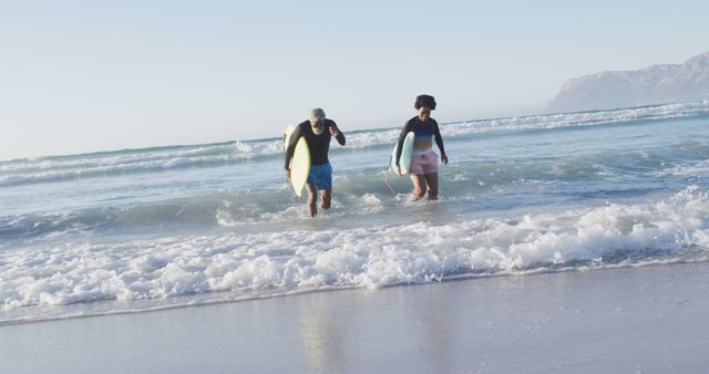 Happy african american couple running with surfboards on sunny beach - Download Free Stock Photos Pikwizard.com