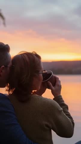 Couple Watching Sunset on Lake While Sipping Coffee and Embracing | Vertical Video