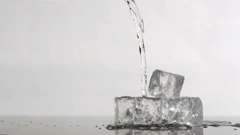 Close-Up of Water Pouring Over Ice Cubes With Grey Background