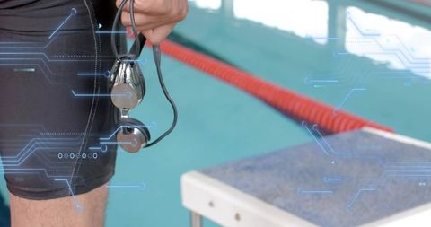 Swimmer holding wired earphones at starting block, preparing for race and training