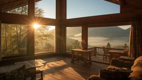 Golden morning light in rustic mountain cabin with panoramic floor-to-ceiling windows